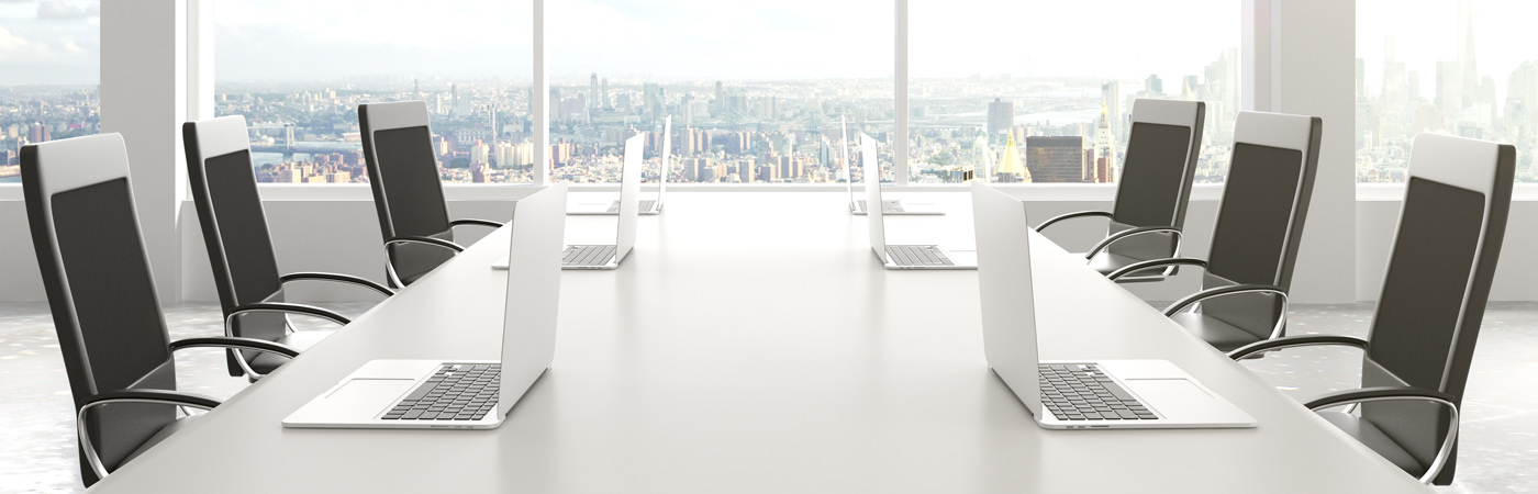 Empty chairs in a high-rise meeting room with laptops on a desk